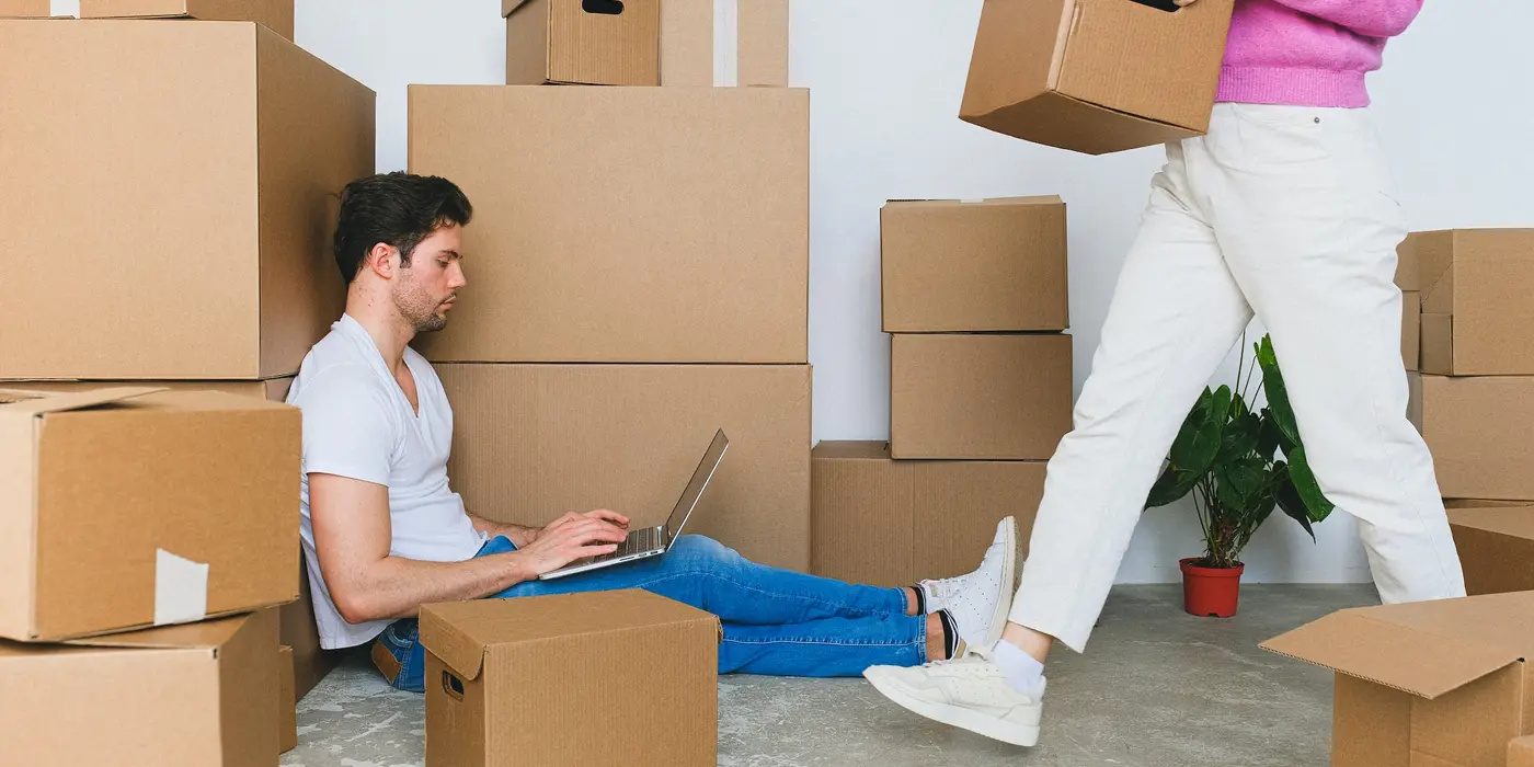 Boxes full of appliances and a man on a computer.